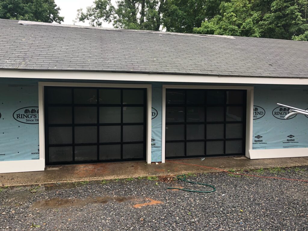 Two black full-view garage doors with rectangular glass panels