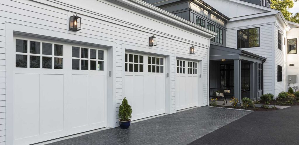 Three white garage doors with divided-light windows at a Connecticut home
