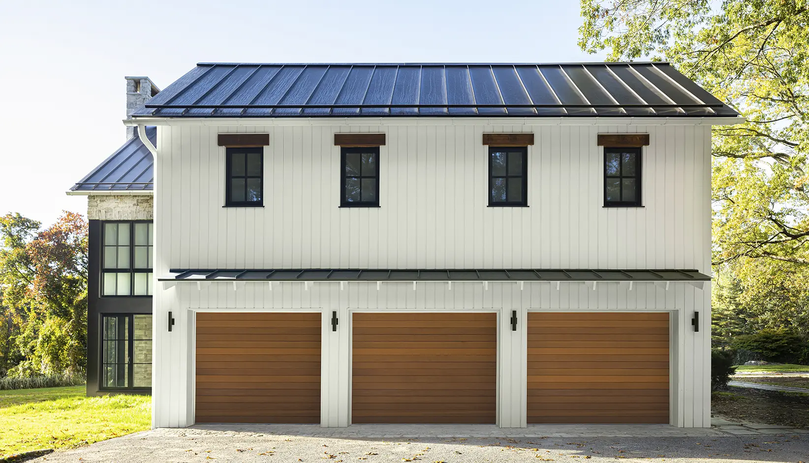 Three Clopay Reserve Wood Modern horizontal cedar garage doors on a white farmhouse